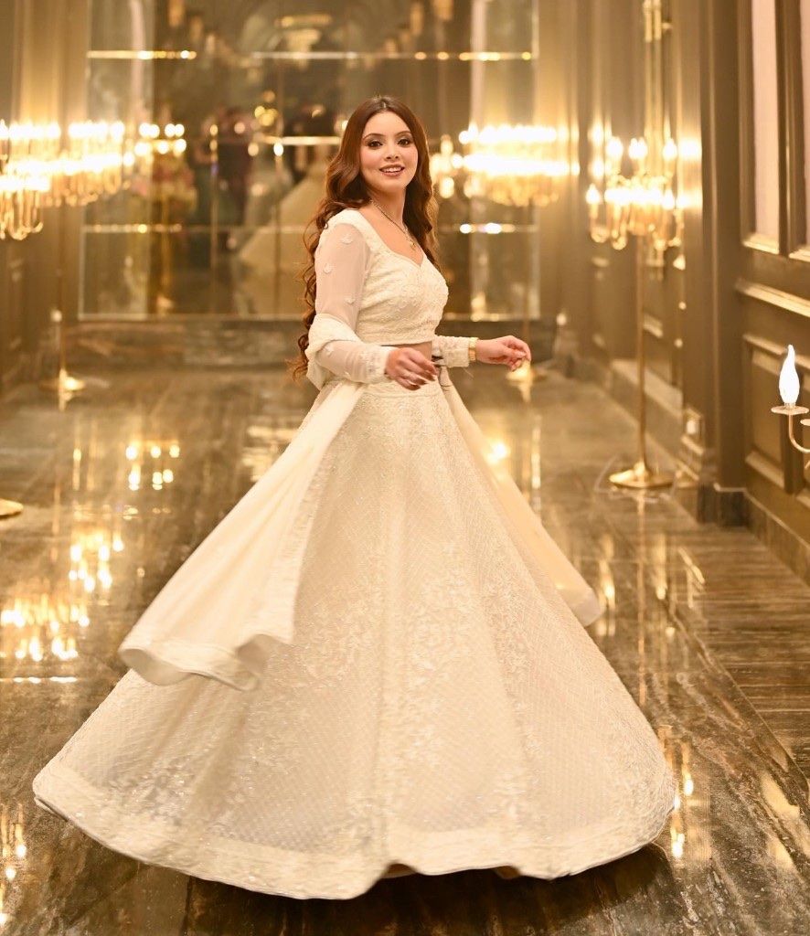 Sakshi twirling in a white embroidered lehenga in a candlelit hallway