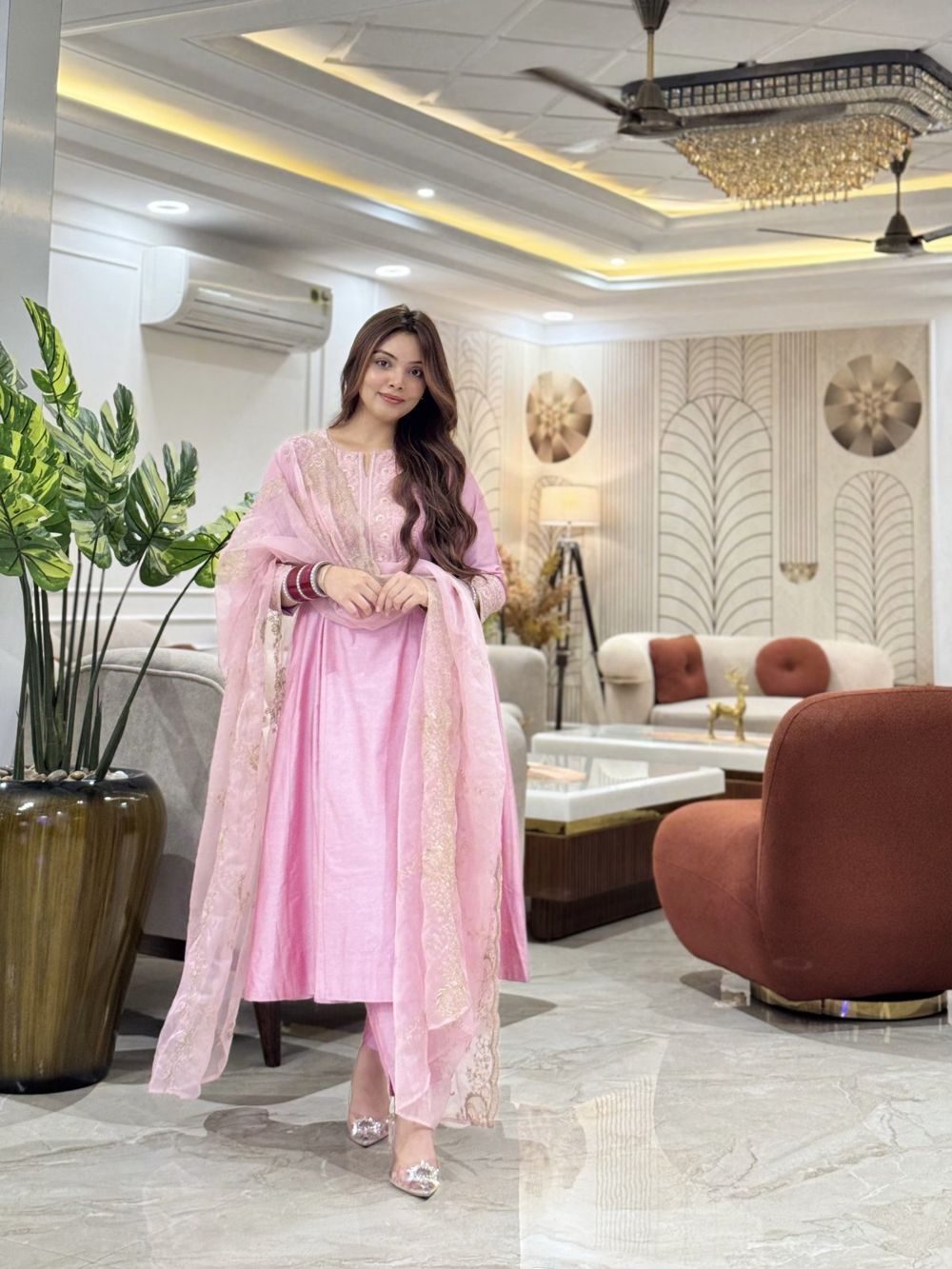 Sakshi in a pink suit in a bright living room